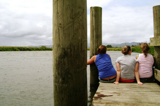 3 junge Frauen sitzen auf einem Steg am See