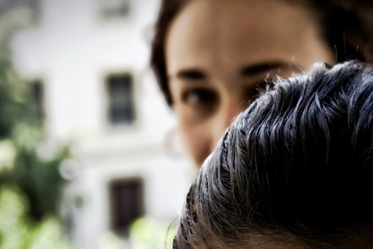 Im Vordergrund die dunklen Haare einer Person, im Hintergrund ein Mädchengesicht