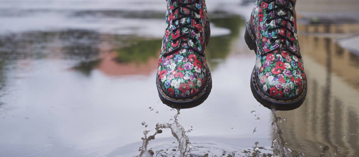 Zwei bunt gemusterte Schuhe, unter den Schuhen ist eine Wasserpfütze zu sehen