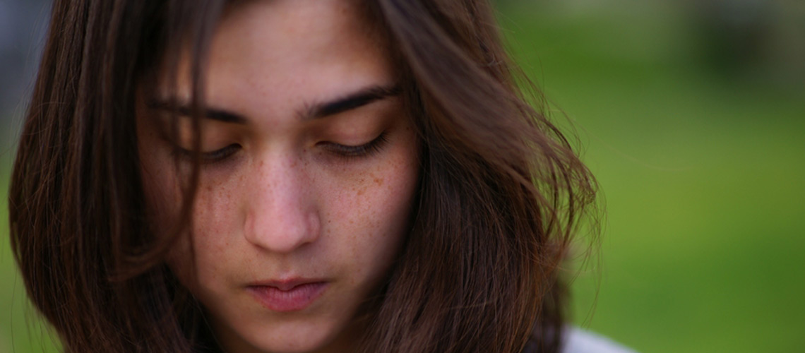 Das Gesicht einer jungen Frau mit ernstem Gesichtsausdruck und langen Haaren